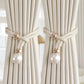 Curtains with decorative tiebacks featuring pearls and gold loops.