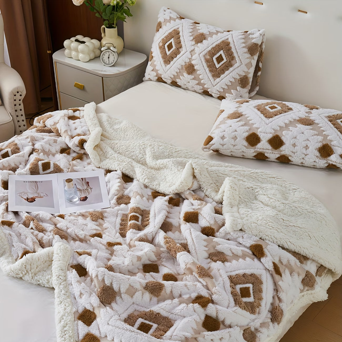 Patterned blanket and pillows on a bed with a side table in the background