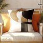 Decorative pillows with abstract patterns on a white cushioned chair.