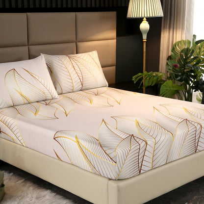 Bed with leaf-patterned bedding, pillows, and a lamp in a room setting.