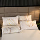 Decorative pillows with leaf patterns on a bed against a brown headboard.