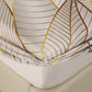 Fitted sheet with gold leaf pattern on a bed