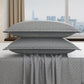 Gray patterned pillows and duvet cover on a bed with a cityscape view.