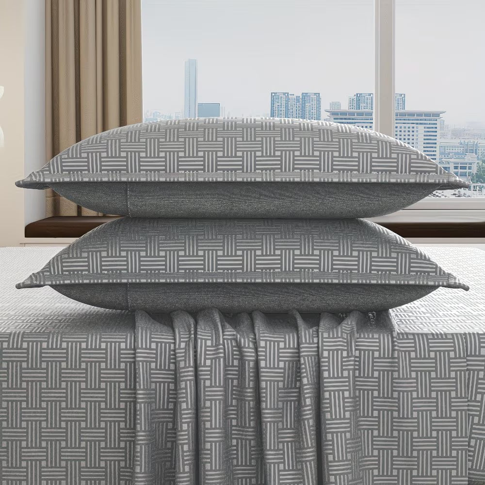 Gray patterned pillows and duvet cover on a bed with a cityscape view.
