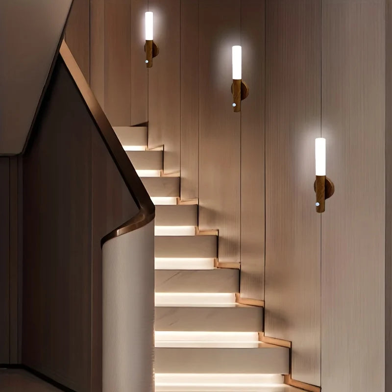 Modern staircase with illuminated steps and wall-mounted lights in a dimly lit setting.