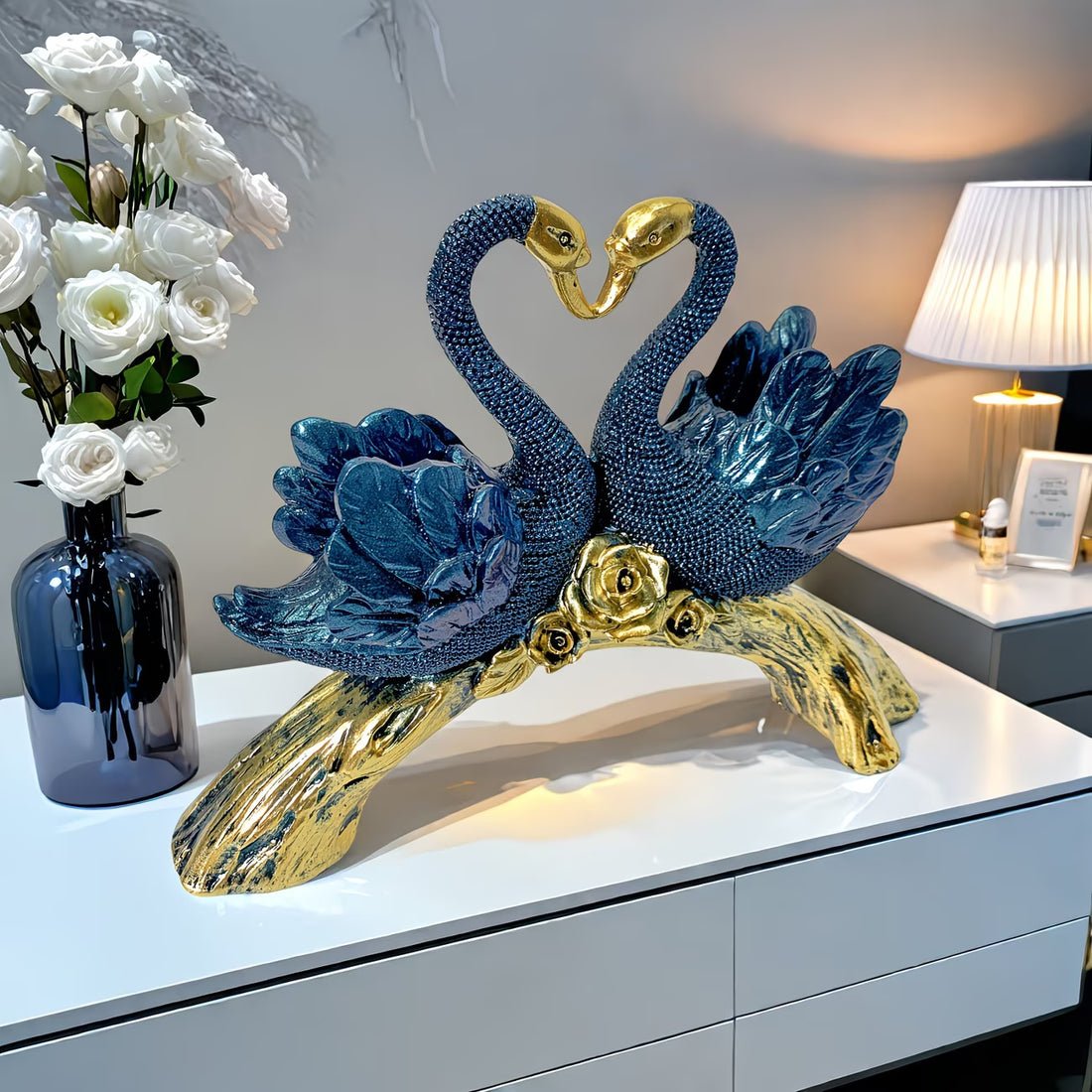 Decorative sculpture of two blue swans with gold accents on a white surface.