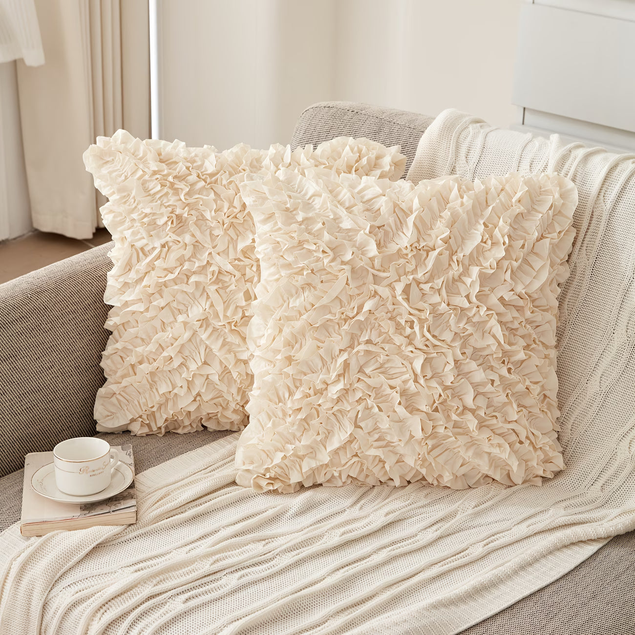 Two textured pillows on a sofa with a cup and book in the foreground.
