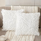 Two white textured pillows on a brown sofa with a cup and saucer in the foreground.
