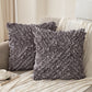 Two gray ruffled pillows on a beige sofa with a cup and saucer in the background.