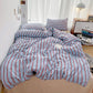 Striped bedding set on a bed in a room with a desk and computer.