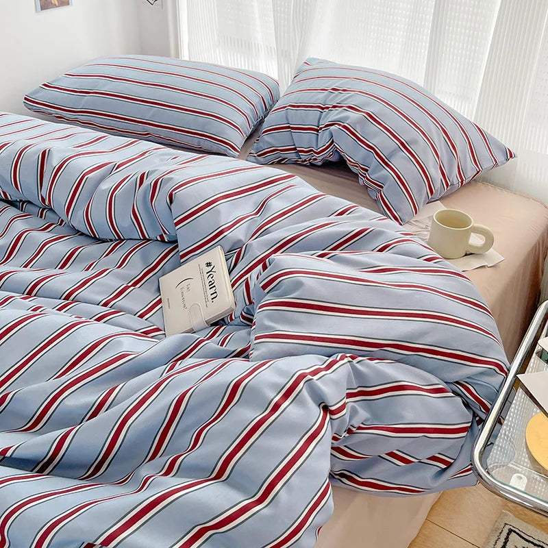Striped bedding with red and blue lines on a bed in a bedroom setting.