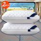 Two white pillows with a blue strap on a reflective surface, with a scenic background of mountains and a van.