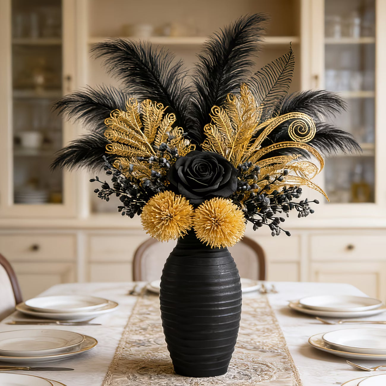 Decorative floral arrangement with black and gold feathers in a black vase on a table.