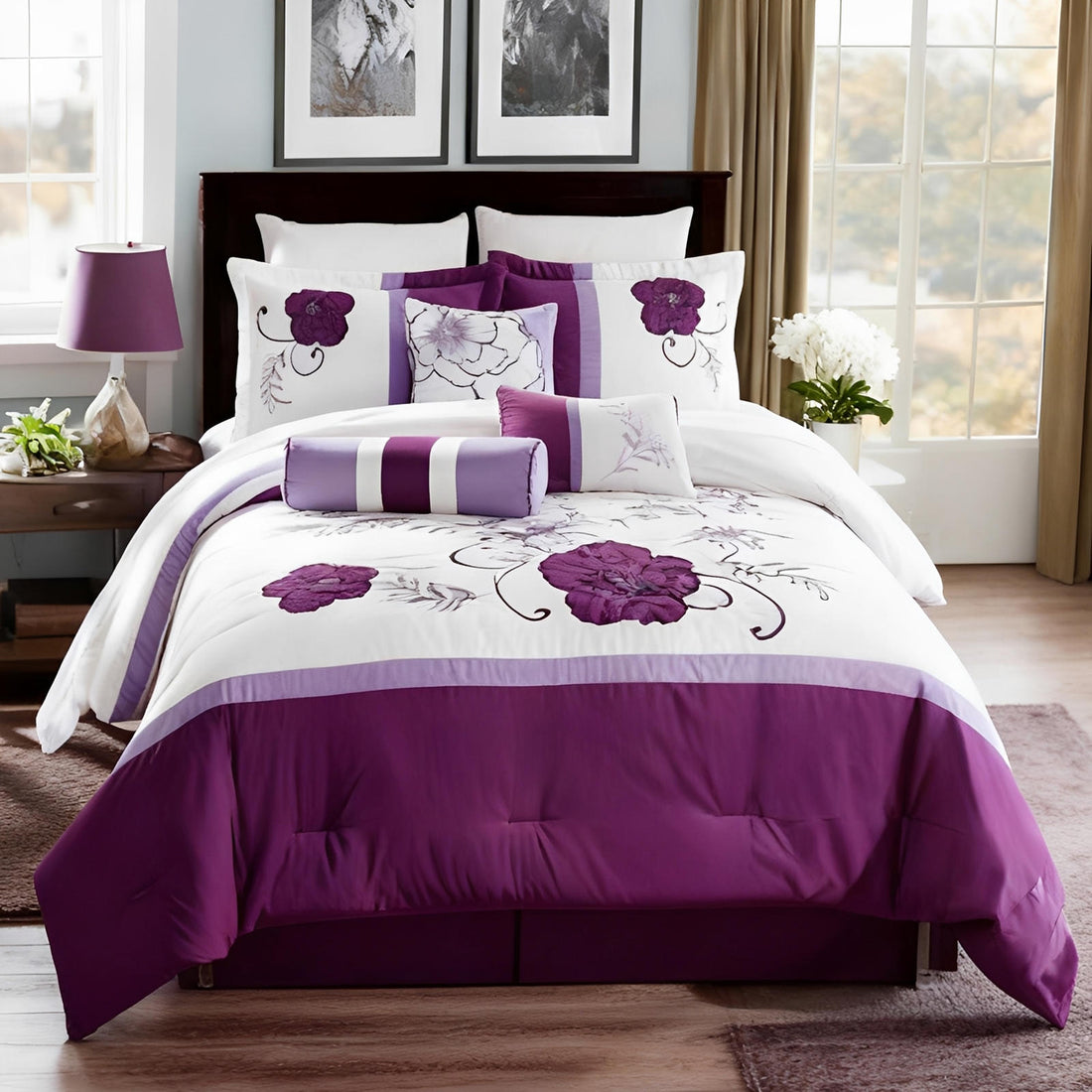 Purple and white floral bedding set on a bed in a room with windows and decor.