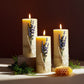 Three lit candles with lavender and honeycomb on a dark background