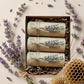 Three rolled-up items in a box with lavender flowers and a honeycomb on a light background