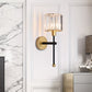 Modern wall sconce with gold and black design on a white wall.