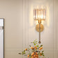Wall-mounted lamp with glass shade and gold finish on a neutral wall.