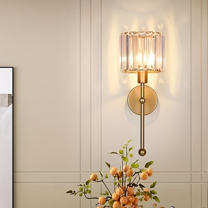 Wall-mounted lamp with glass shade and gold finish on a neutral wall.