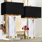 Two black table lamps with gold bases on a decorative shelf.