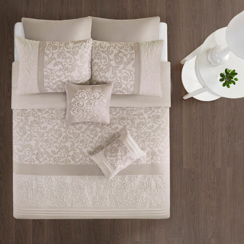 Neatly arranged bed with patterned bedding on a wooden floor.