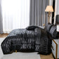 Black striped bedding set on a bed in a bedroom with curtains and a lamp.
