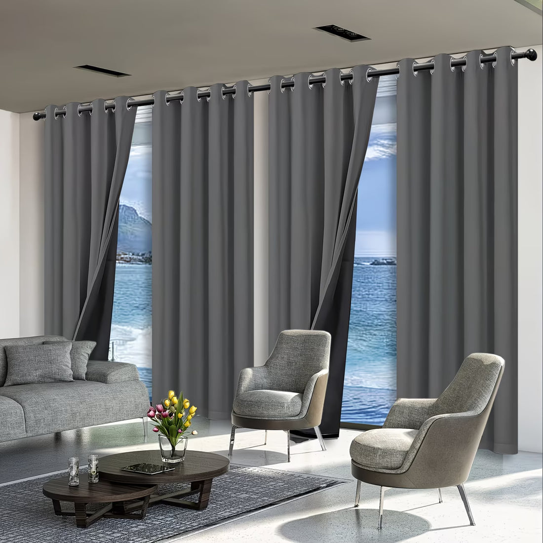 Modern living room with gray curtains, sofa, and chairs overlooking a scenic view.