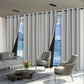 Living room with large windows draped with gray curtains, featuring a sofa, coffee table, and chairs.