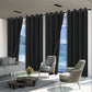 Modern living room with black curtains, gray sofa, and chairs overlooking a scenic view.
