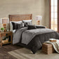 Bedroom with gray comforter set on a bed, wooden headboard, and lamps.