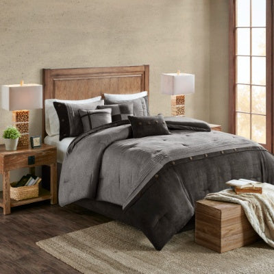 Bedroom with gray comforter set on a bed, wooden headboard, and lamps.