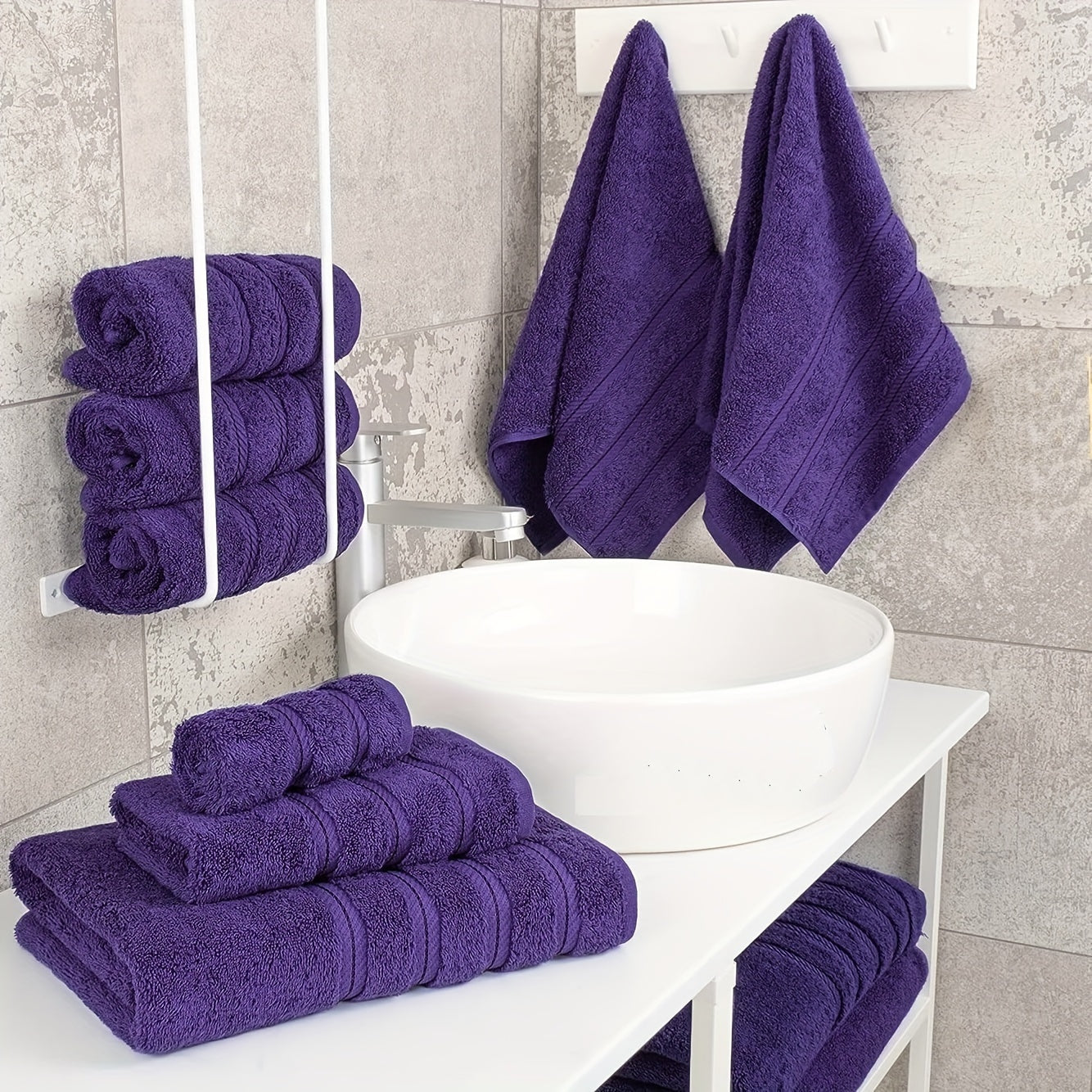 Purple towels on a bathroom counter with a mirror reflecting the towels.