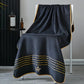 Black towel with gold accents draped over a chair in a room setting.