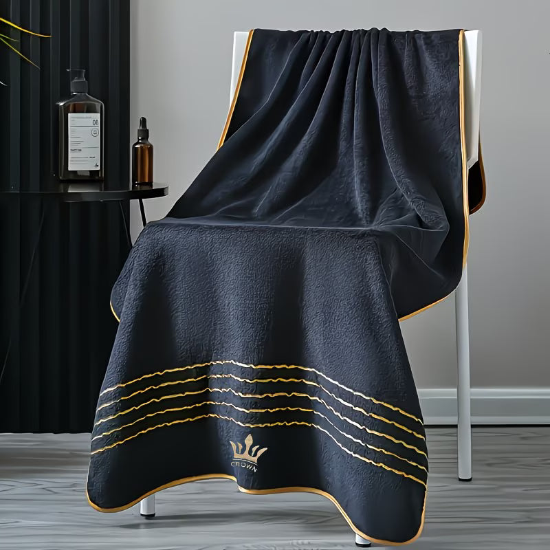 Black towel with gold accents draped over a chair in a room setting.
