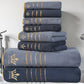 Stack of blue towels with gold embroidery on a bathroom counter.