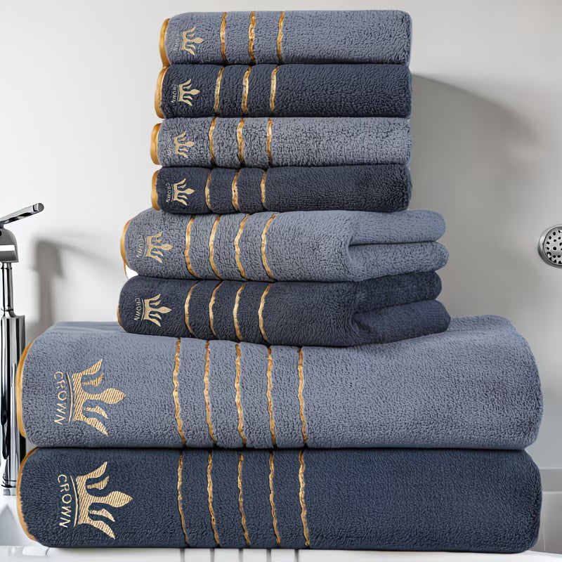 Stack of blue towels with gold embroidery on a bathroom counter.