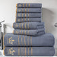 Stack of gray towels with gold accents and a logo on a bathroom counter.