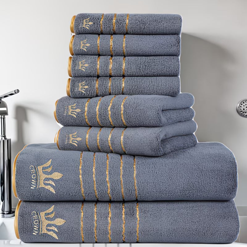 Stack of gray towels with gold accents and a logo on a bathroom counter.