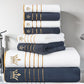 Stack of white and navy blue towels with gold accents on a bathroom counter.