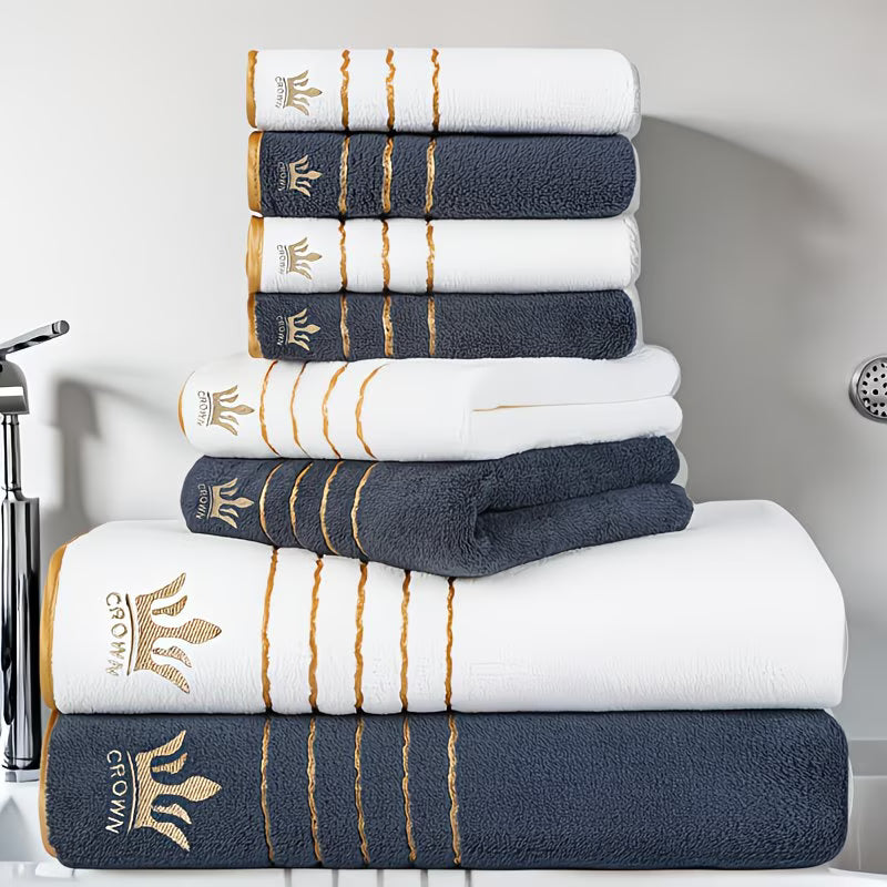 Stack of white and navy blue towels with gold accents on a bathroom counter.