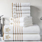 Stack of white towels with gold embroidery on a bathroom counter