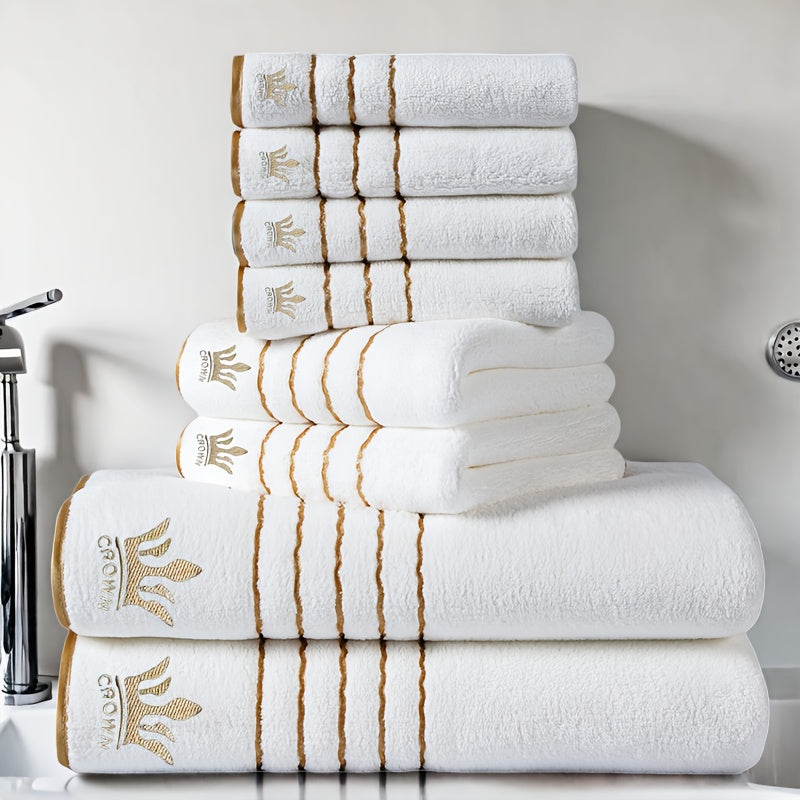 Stack of white towels with gold embroidery on a bathroom counter