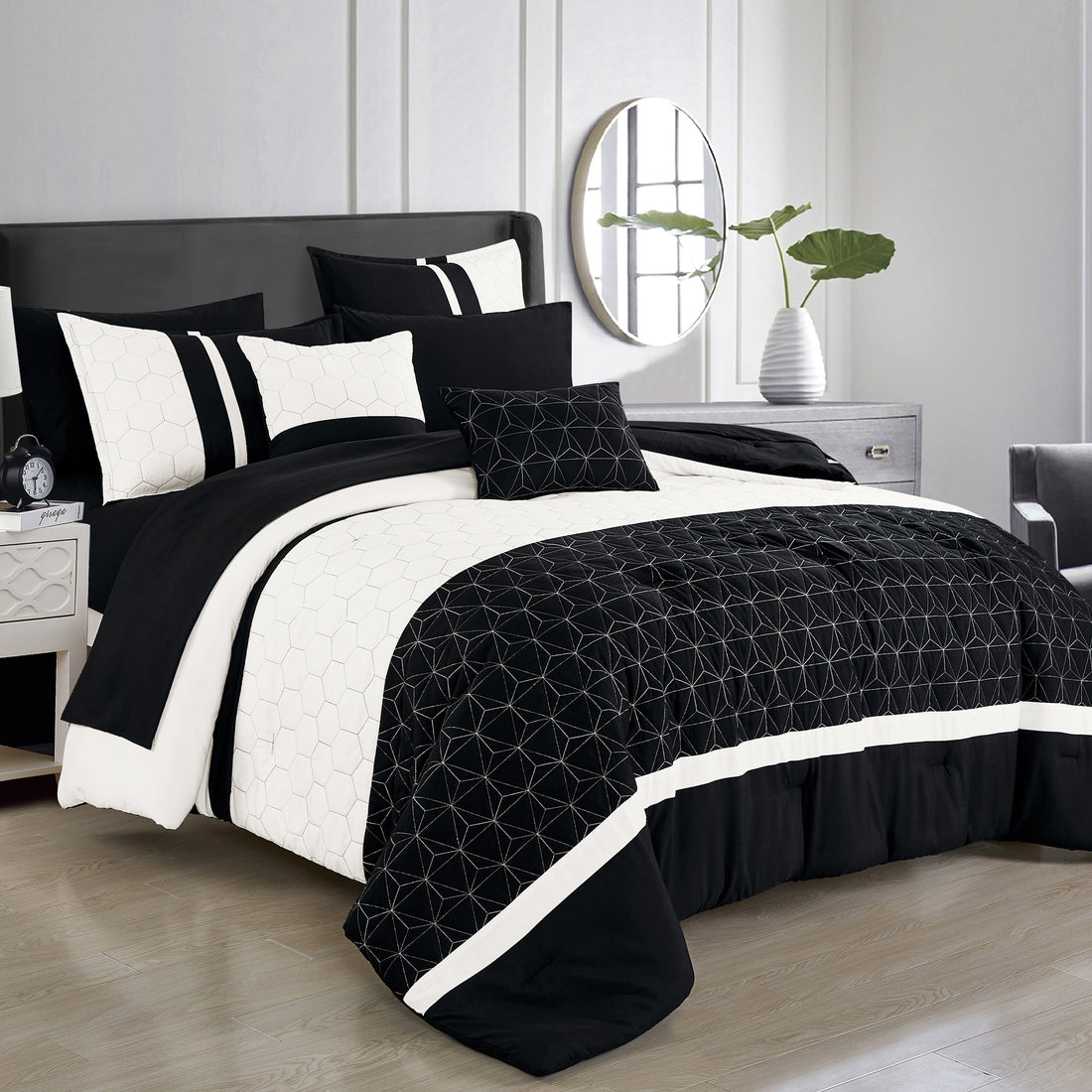 Black and white bedding set on a bed in a bedroom with a mirror and plant in the background.
