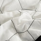 Close-up of a white quilt with black geometric patterns
