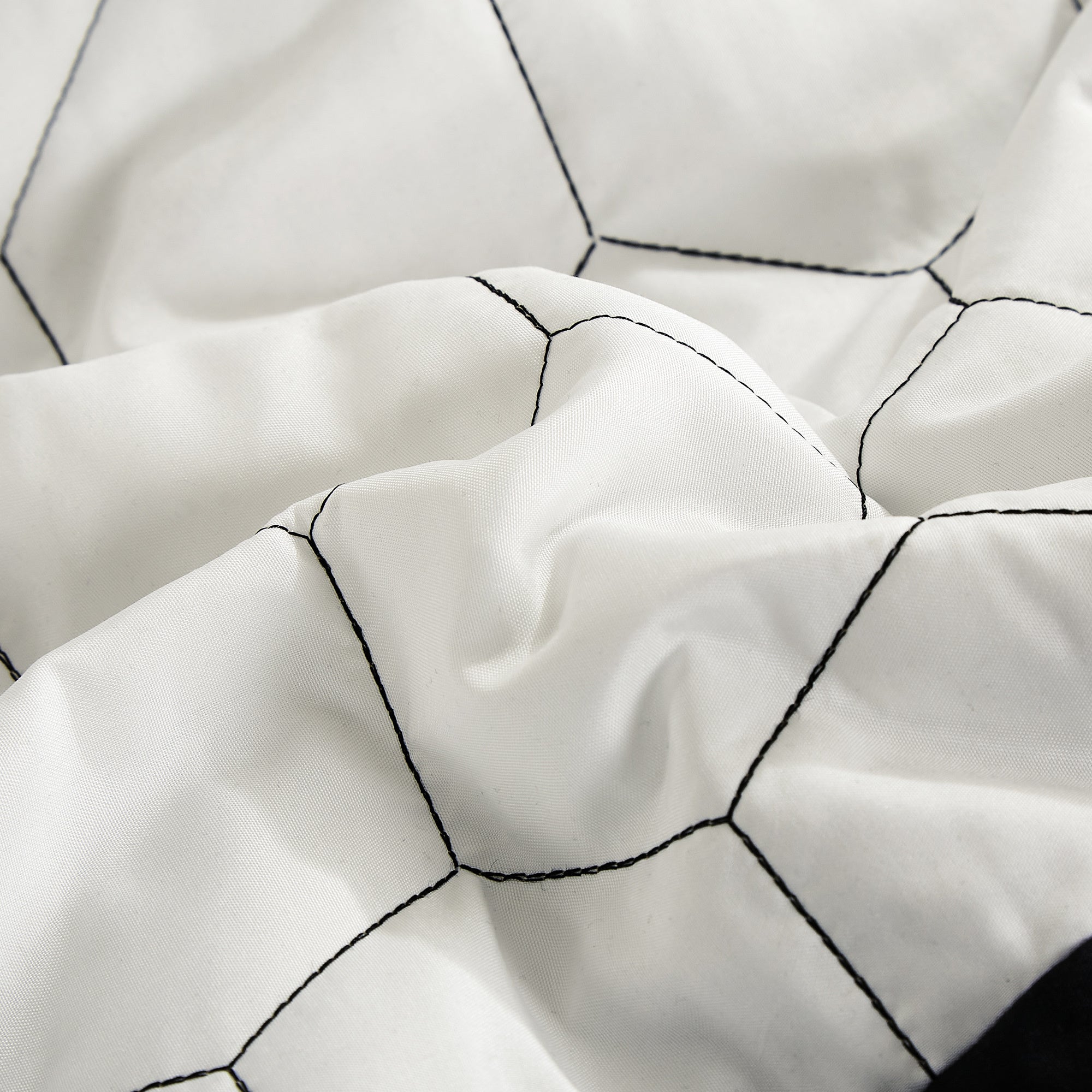 Close-up of a white quilt with black geometric patterns