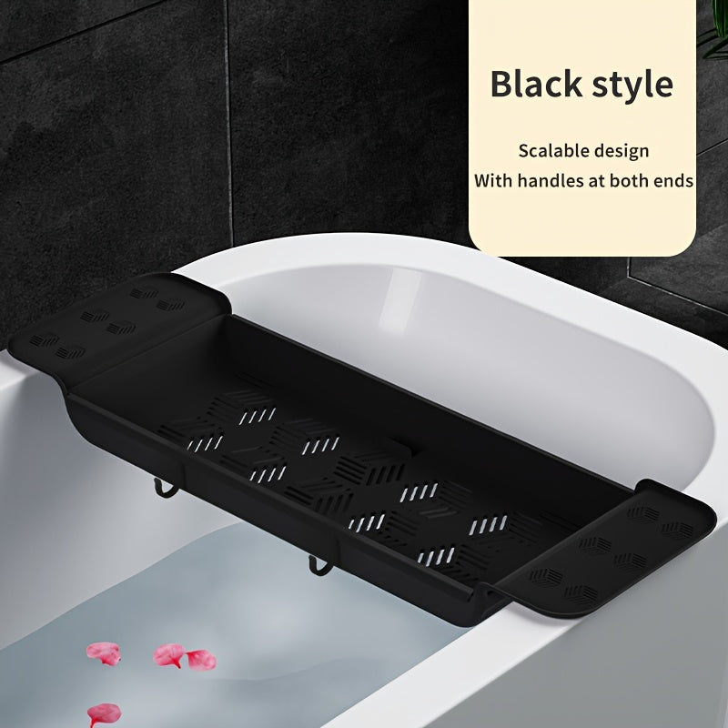 Black bathtub caddy with handles placed on a white bathtub with black tiles in the background.