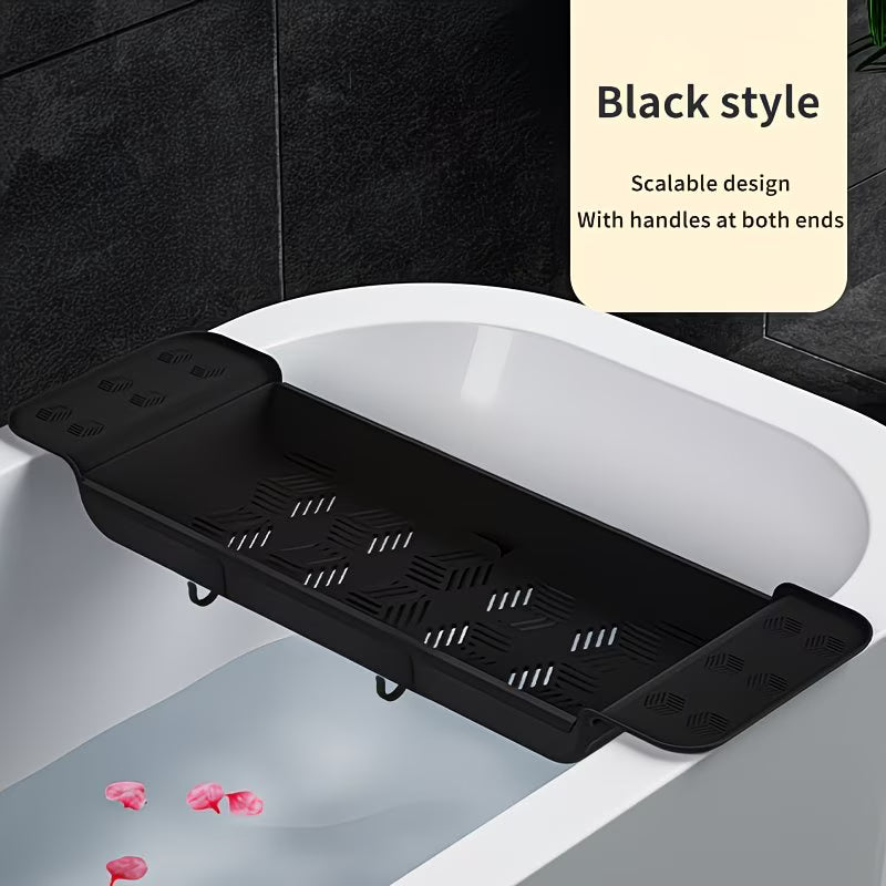 Black bathtub caddy with handles placed on a white bathtub with black tiles in the background.