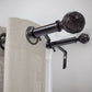 Curtain rod with decorative finials and beige curtains against a white wall