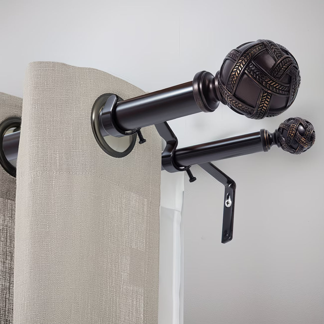 Curtain rod with decorative finials and beige curtains against a white wall