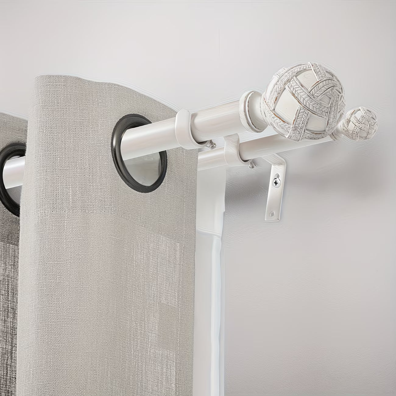 Curtain rod with decorative finials and gray curtains on a plain background